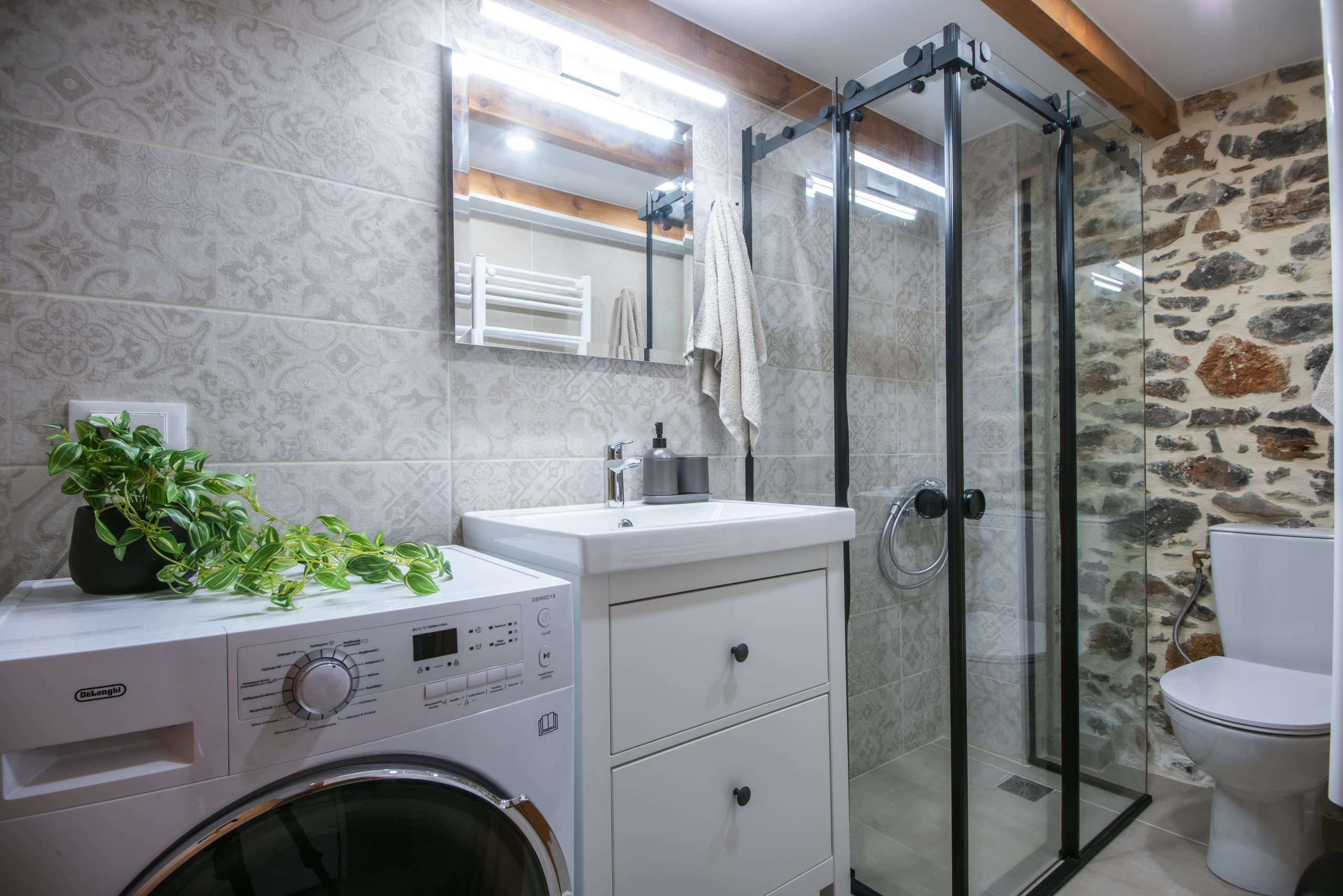 Walk-in shower, washbasin, washing machine and stone wall