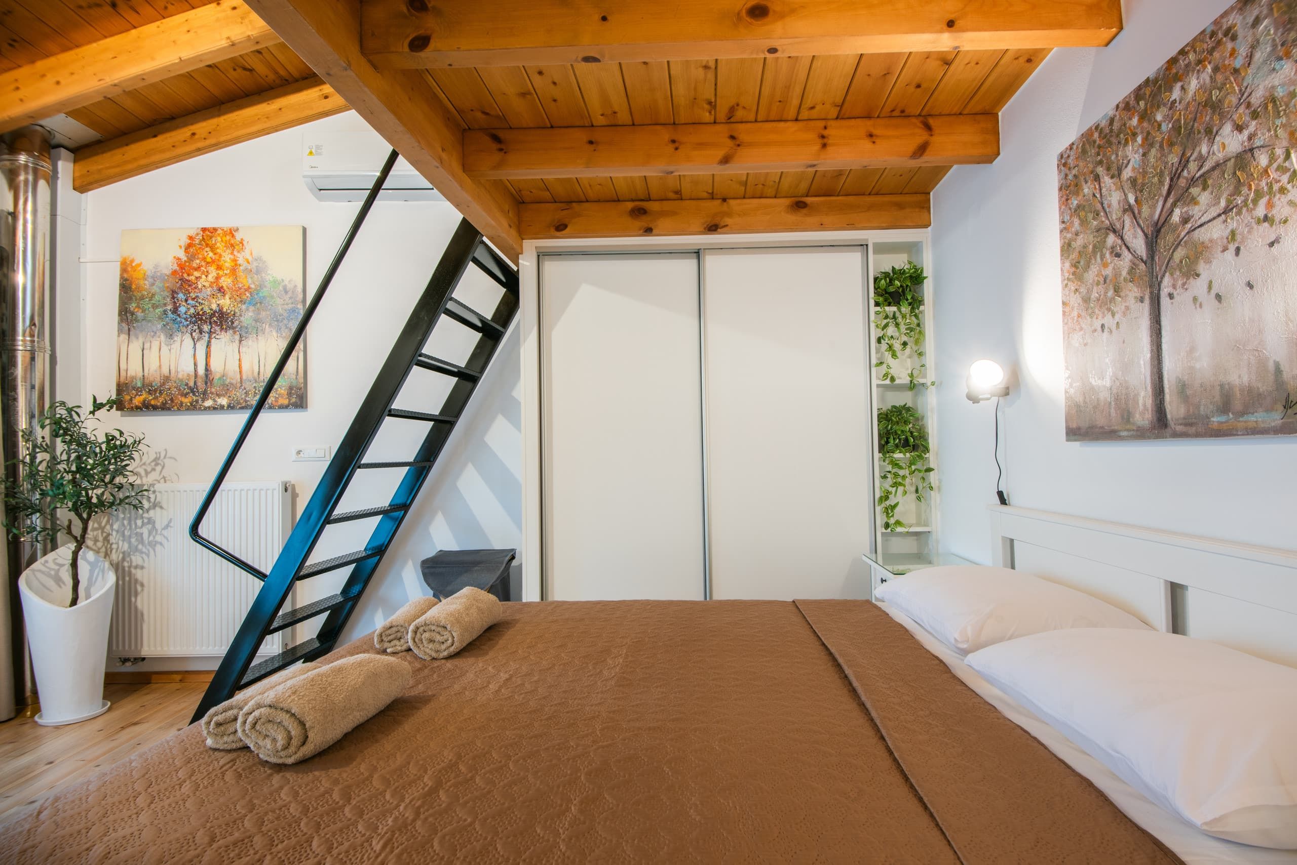 Steep black metal stair leading up to the οντάς above the bedroom