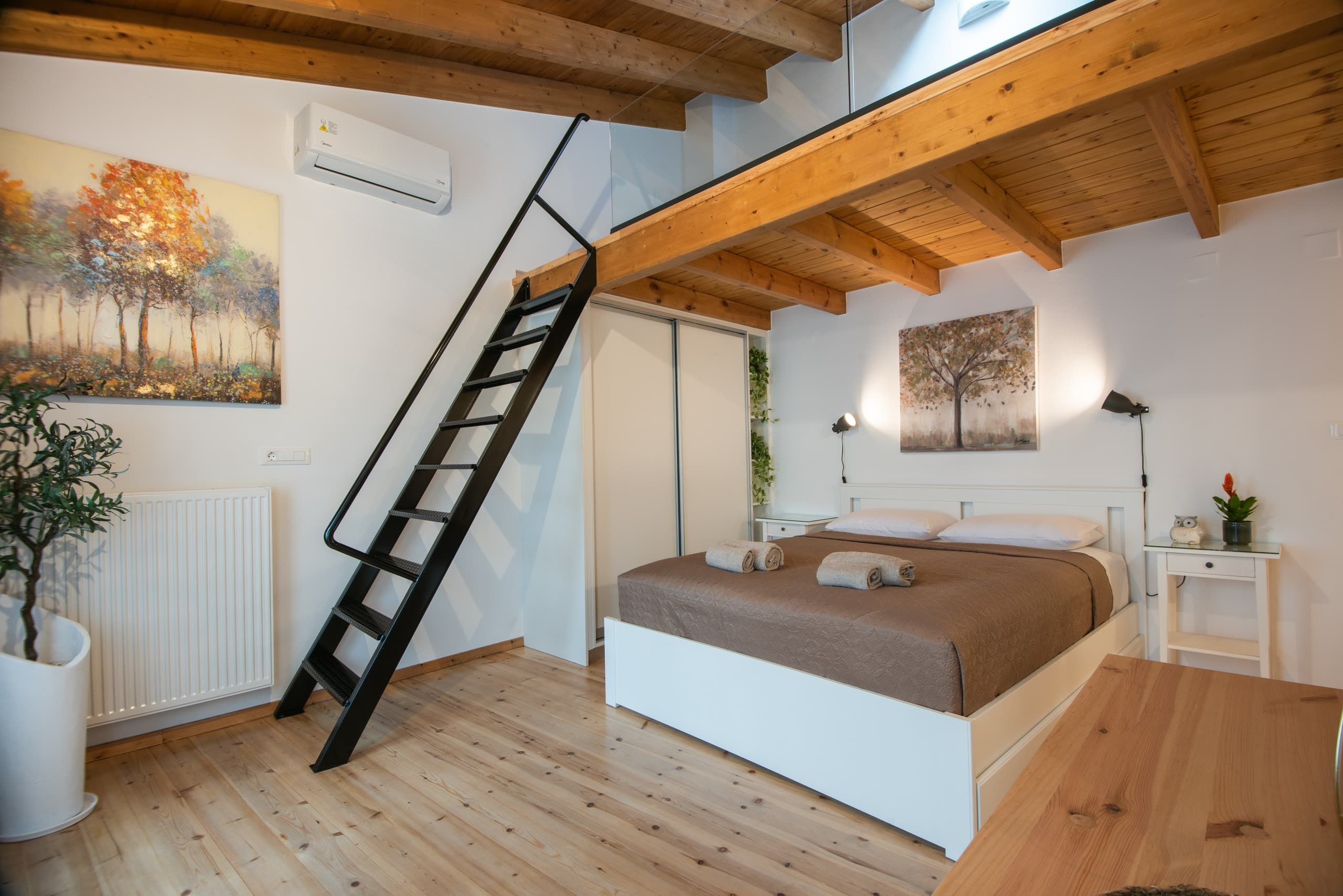 Double bed, stair and a painting of trees